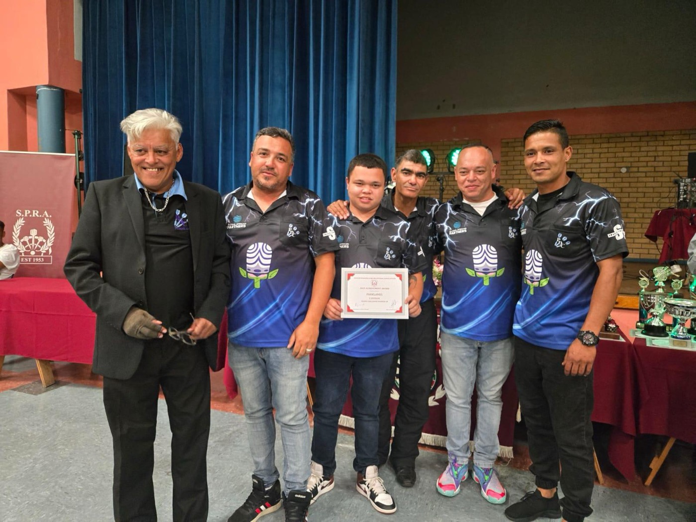 Parklands players receiving a certificate at an SPRA presentation, with trophies displayed on the table alongside